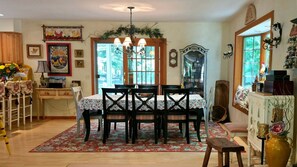 A dining area with a wooden table, chairs, and a chandelier. There is a window with a view of trees and a clock on the wall. - 3BR Birchwood Pines in Harbor Springs with WiFi, and fireplace. (Harbor Springs)
