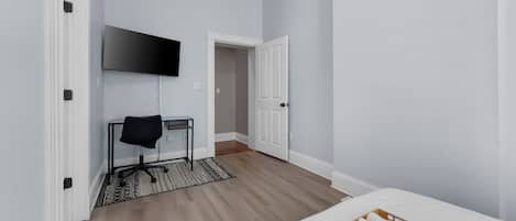 Une chambre d’hôtel comprenant un lit, un téléviseur fixé au mur, un bureau avec une chaise et un plateau en bois avec des serviettes.
