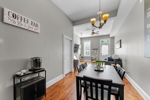 A dining area with a coffee station, a chandelier, and a view of the living room. - The Benton Lounge "Historic Home Near Downtown" (St. Louis)