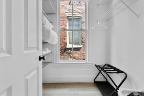 A narrow room with a white door, a window with a brick wall view, and a black metal rack. - The Benton Lounge "Historic Home Near Downtown" (St. Louis)
