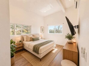 A modern bedroom with a large bed, bedside tables, a desk, and a TV mounted on the wall. - Golden Hill Retreat with Private Hot Tub (Spring Valley)