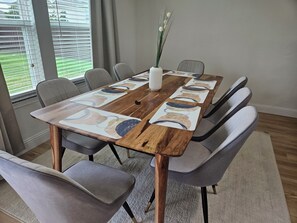 A dining table with a wooden top and a decorative runner, surrounded by six grey upholstered chairs.