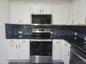A kitchen with white cabinets, a black countertop, a stainless steel oven, and a microwave. - Cozy 3 Bedroom Home Near Frisco's Best Spots- Stylish&Comfy (Little Elm)