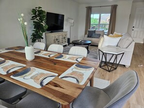 A modern living room with a dining table, sofa, and television. - Cozy 3 Bedroom Home Near Frisco's Best Spots- Stylish&Comfy (Little Elm)