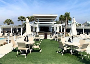 A poolside area with artificial grass, lounge chairs, and umbrellas. - BlueNote by Sandpiper | Near North Beach (Seabrook Island)