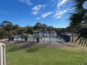 A tennis court with a building in the background. - BlueNote by Sandpiper | Near North Beach (Seabrook Island)
