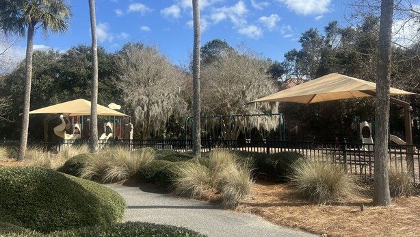 A park with a playground, palm trees, and a covered seating area. - BlueNote by Sandpiper | Near North Beach (Seabrook Island)