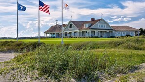 A large house with a porch, two flags, and a grassy field. - BlueNote by Sandpiper | Near North Beach (Seabrook Island)