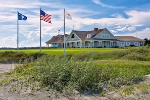 A large house with a porch, two flags, and a grassy field. - BlueNote by Sandpiper | Near North Beach (Seabrook Island)