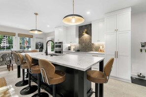 A modern kitchen with a central island, bar stools, and pendant lighting. - Newly Renovated. Discounted prices through May 1. The Retreat by Sandpiper | Near Beach (Seabrook Island)
