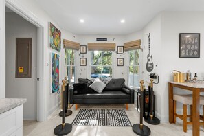 Ein modernes Wohnzimmer mit einer schwarzen Ledersofa, einem gemusterten Teppich und einem Essbereich mit einem Holztisch und Stühlen.