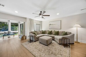 Ein modernes Wohnzimmer mit einem Ecksofa, einem Deckenventilator und einer Stehlampe.
