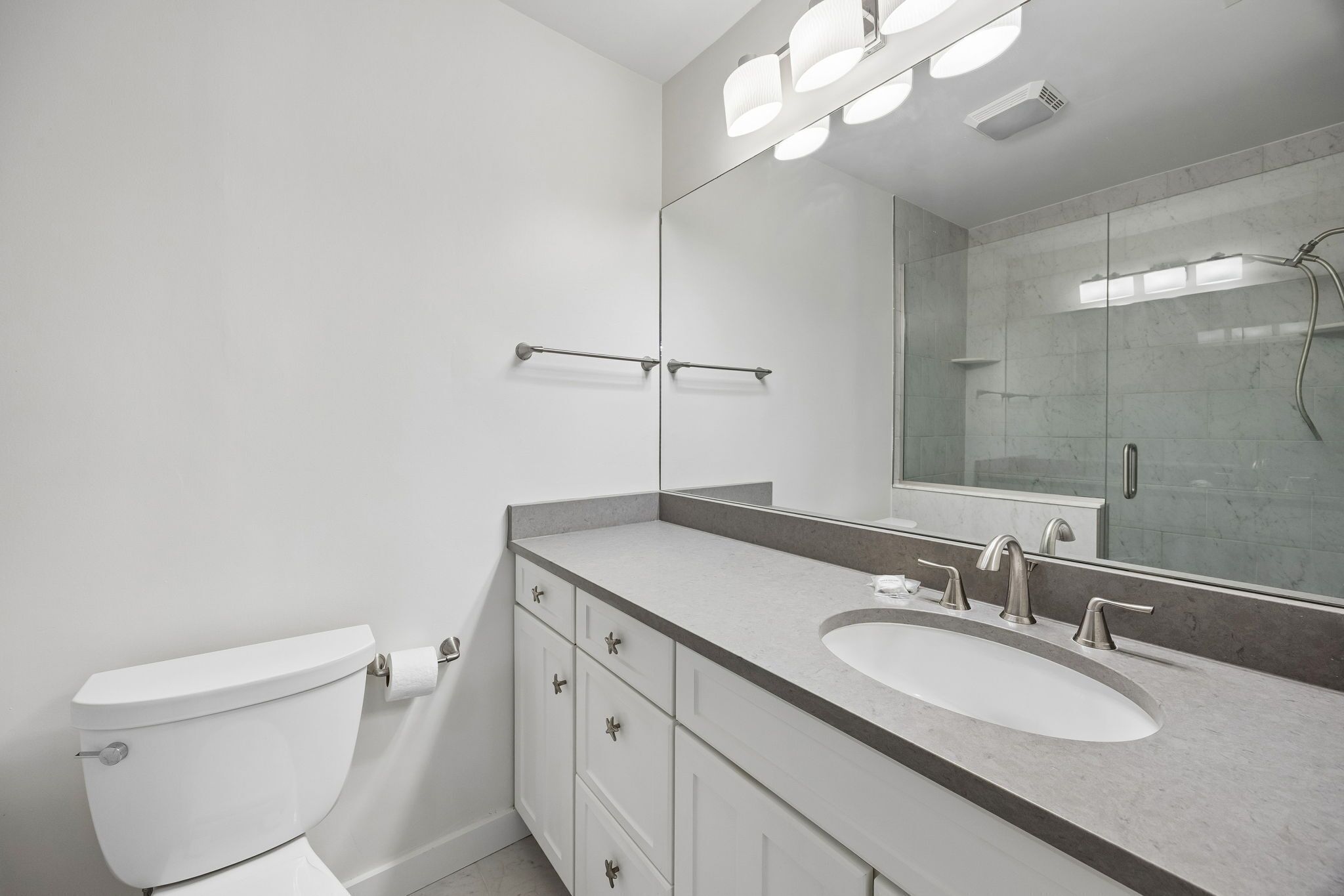 A modern bathroom with a toilet, a sink, and a shower.