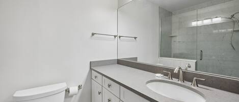 A modern bathroom with a toilet, a sink, and a shower.