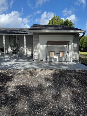 Ein Haus mit überdachter Veranda, einer Hängematte und einer Garage.