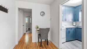 A hallway leading to a bathroom and a kitchen area with blue cabinets.