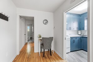 A hallway leading to a bathroom and a kitchen area with blue cabinets.