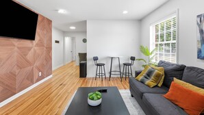 A modern living room with a sofa, coffee table, and a TV mounted on a wooden wall.