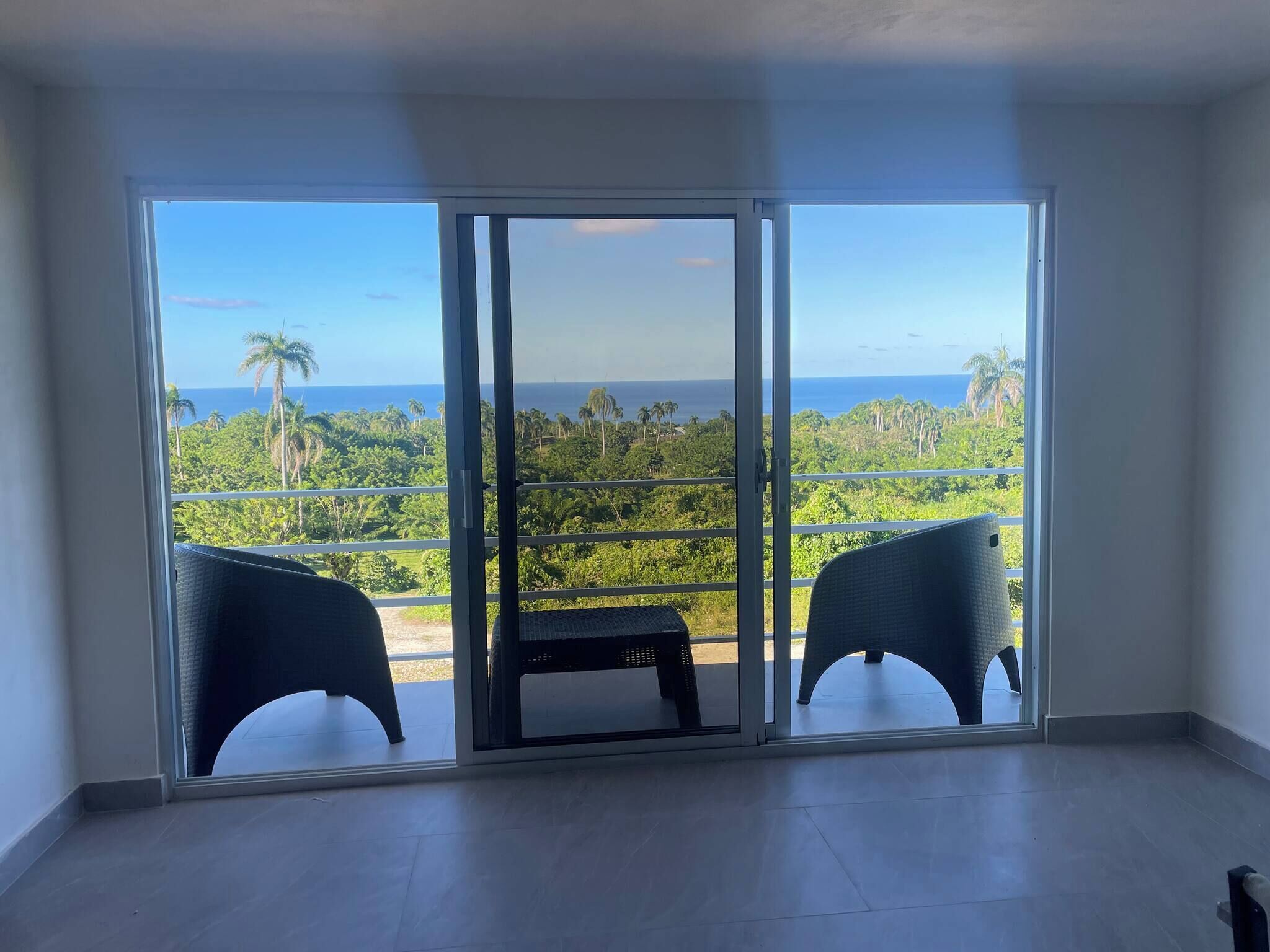A room with a large sliding glass door leading to a balcony with two chairs and a table.