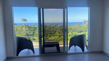 A room with a large sliding glass door leading to a balcony with two chairs and a table.