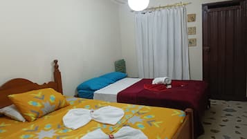 A hotel room with two beds, a wooden headboard, a white ceiling, a window with white curtains, and a door with a brown frame.
