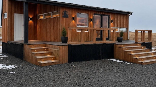 Una cabaña de madera con un porche, escalones y una puerta.