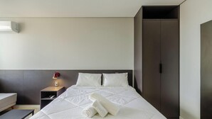 A hotel room with a bed, a nightstand, a lamp, and a wardrobe. - Studio w/ Pool in Center, POA Tco1003 (Porto Alegre)