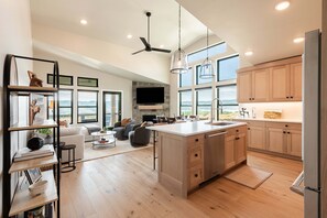 A spacious living area with a large island, a fireplace, and a view of the outdoors. - Min to Deer Valley East Newest Terrain, Community Amenities, Free Ski Shuttle (Heber City)