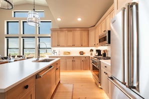 A modern kitchen with wooden cabinets, stainless steel appliances, and a large island with a sink. - Min to Deer Valley East Newest Terrain, Community Amenities, Free Ski Shuttle (Heber City)