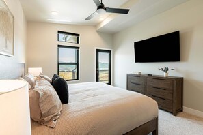 A bedroom with a bed, a dresser, a television mounted on the wall, and two windows offering a view of the outdoors. - Min to Deer Valley East Newest Terrain, Community Amenities, Free Ski Shuttle (Heber City)