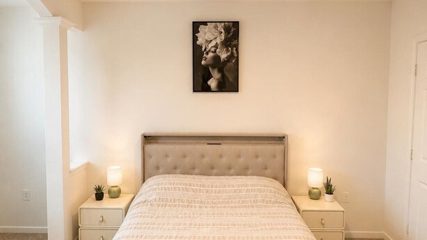 A bedroom with a bed, nightstands, a ceiling fan, and a wall-mounted picture. - Stylish 1BR Resort Retreat Near The Woodlands (Conroe)