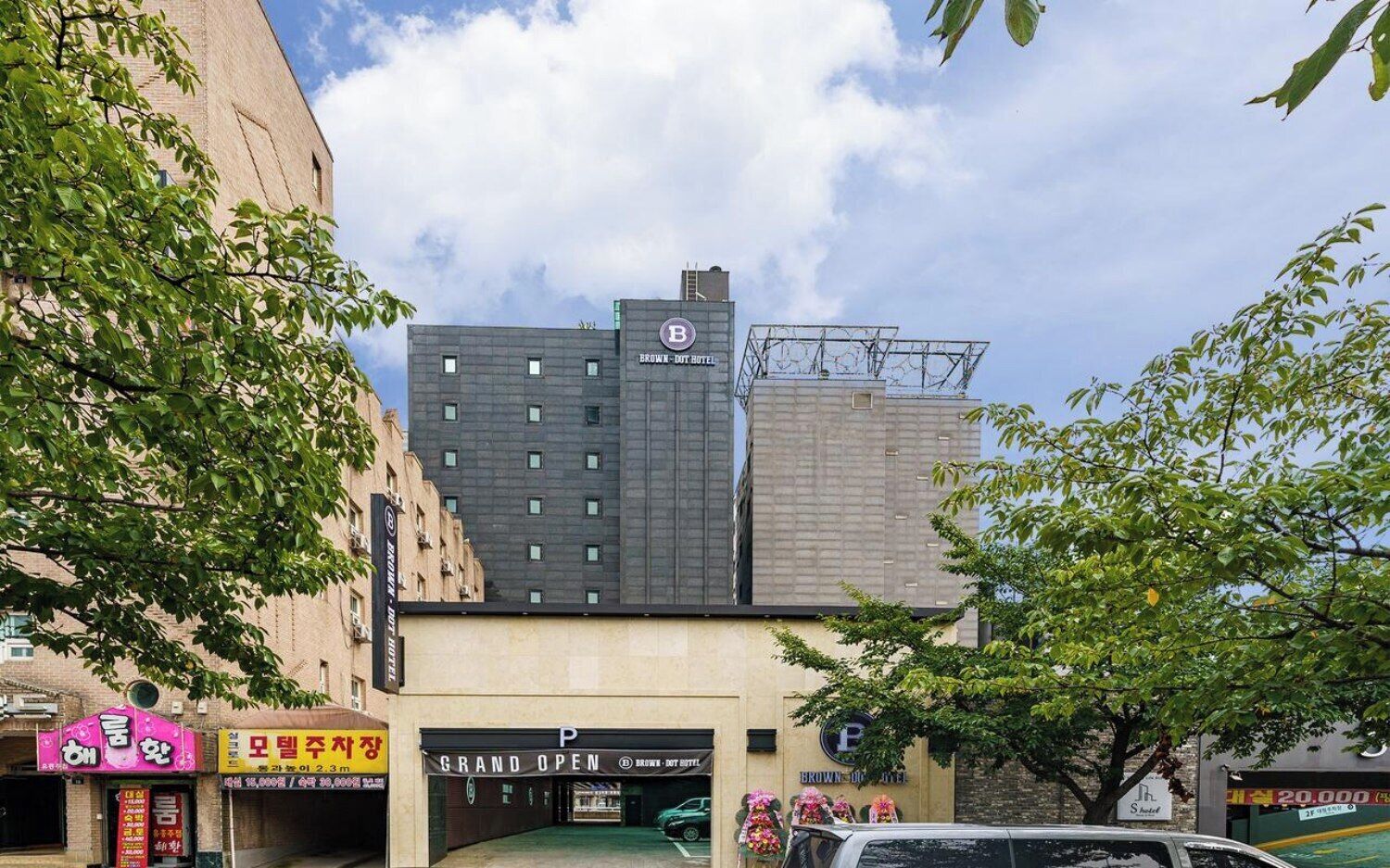 A hotel with a modern design, a parking area, and a storefront with signage.