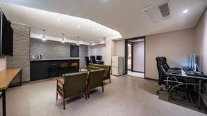 Una habitación de hotel moderna con kitchenette, zona de estar y escritorio con computadoras.
