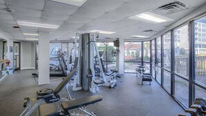 Ein Fitnessstudio mit unterschiedlichen Trainingsgeräten, großen Fenstern und Blick ins Freie.