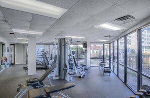 Ein Fitnessstudio mit unterschiedlichen Trainingsgeräten, großen Fenstern und Blick ins Freie.