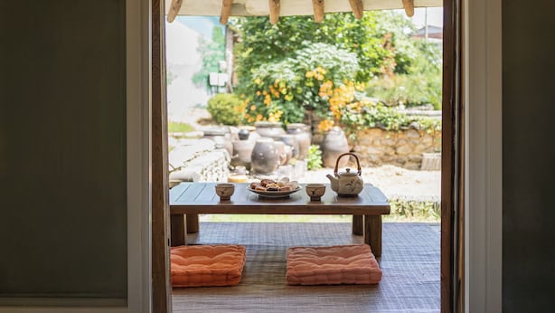 A wooden table with a teapot, cups, and a plate of pastries, set on a tatami mat with cushions. - Gyeongju Hanok Stay Damso (Gyeongju)