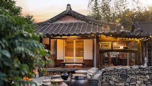 A traditional wooden structure with a tiled roof, a bench, and a stone wall. - Gyeongju Hanok Stay Damso (Gyeongju)