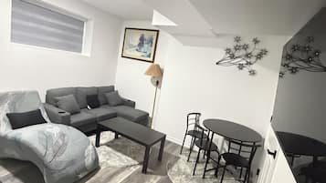 Een moderne woonkamer met een grijze bank, een salontafel en een eethoek met stoelen en een tafel.