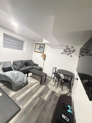 Een moderne woonkamer met een grijze bank, een salontafel en een eethoek met stoelen en een tafel.