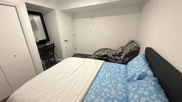 Een slaapkamer met een bed, een bureau en een deur.