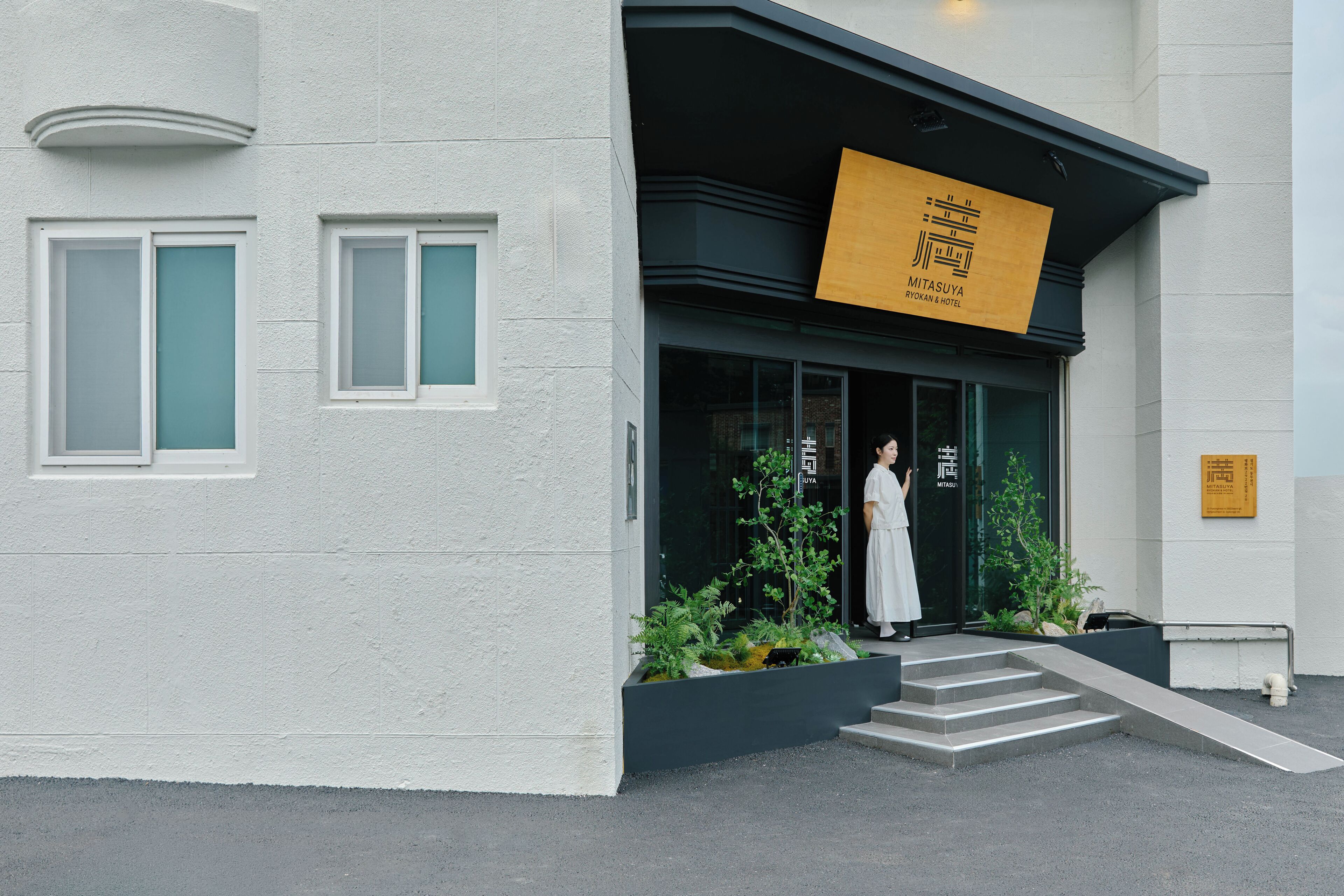 Un edificio con un letrero que dice 'Mitasuya Ryokan & Hotel' y una persona parada en la entrada.