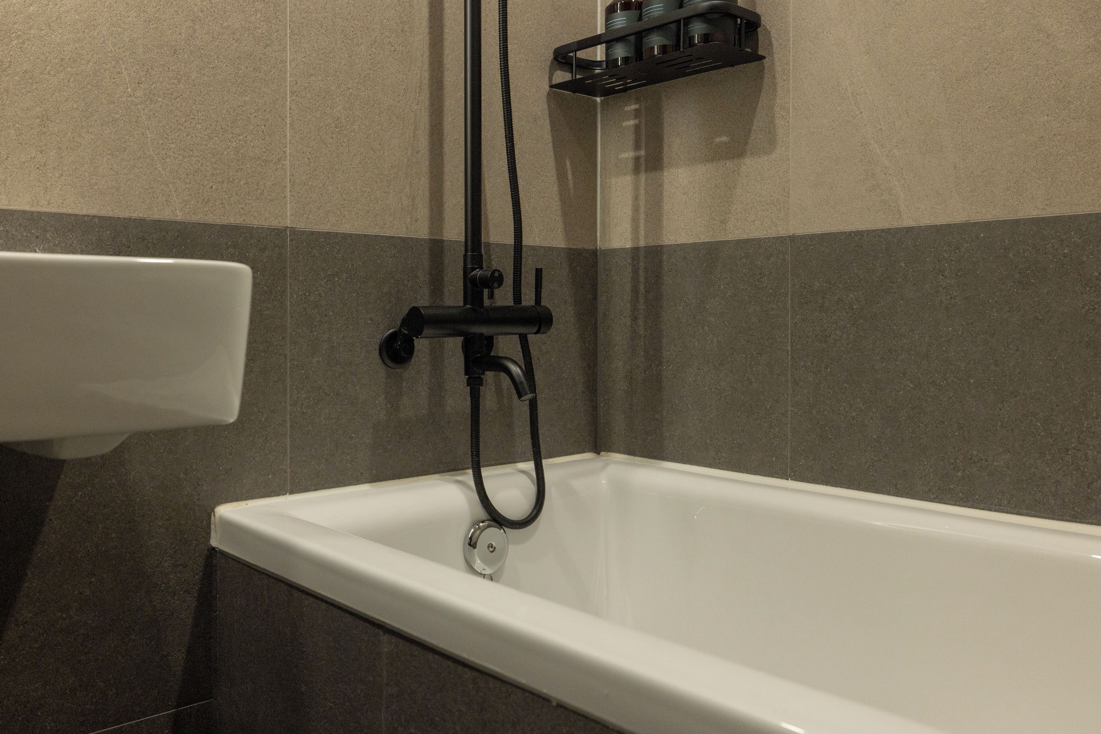 A bathroom with a bathtub, a shower head, and a faucet.