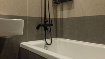 A bathroom with a bathtub, a shower head, and a faucet.