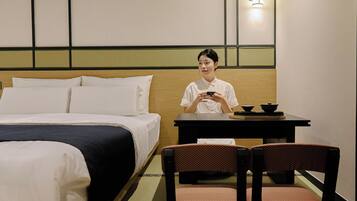 A hotel room with a bed, a table with a tea set, and two chairs.