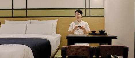 A hotel room with a bed, a table with a tea set, and two chairs.