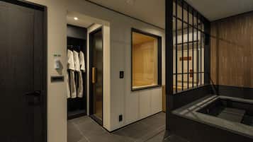 Una habitación de hotel moderna con suelo de madera, un ventanal grande, una bañera integrada y un perchero.