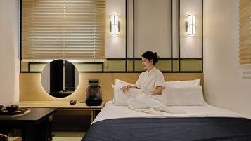 Una habitación de hotel con cama, mesita de noche, lámpara y espejo.