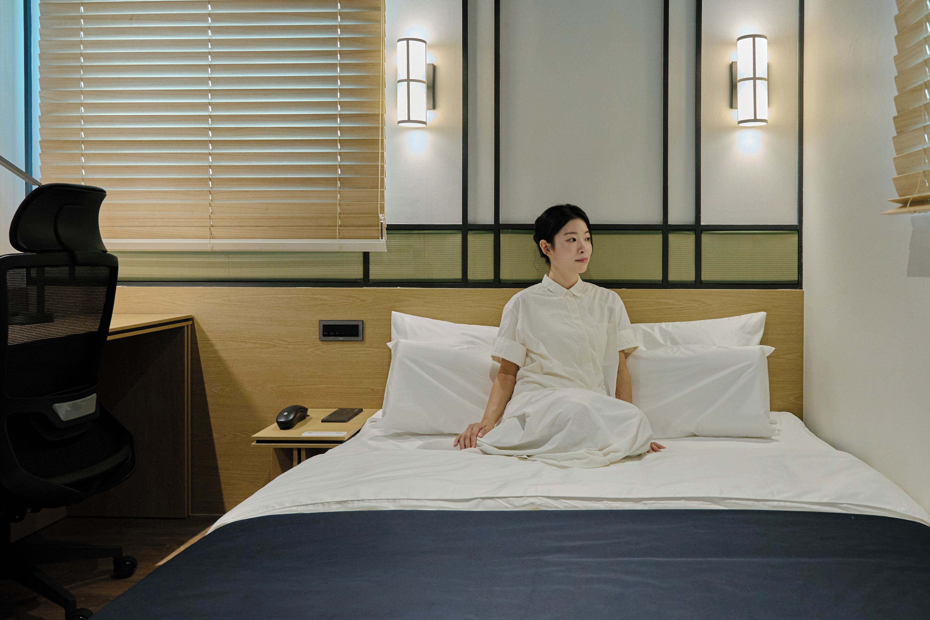 Ein Hotelzimmer mit einem Bett, einem Schreibtisch mit Stuhl und zwei Wandleuchten.