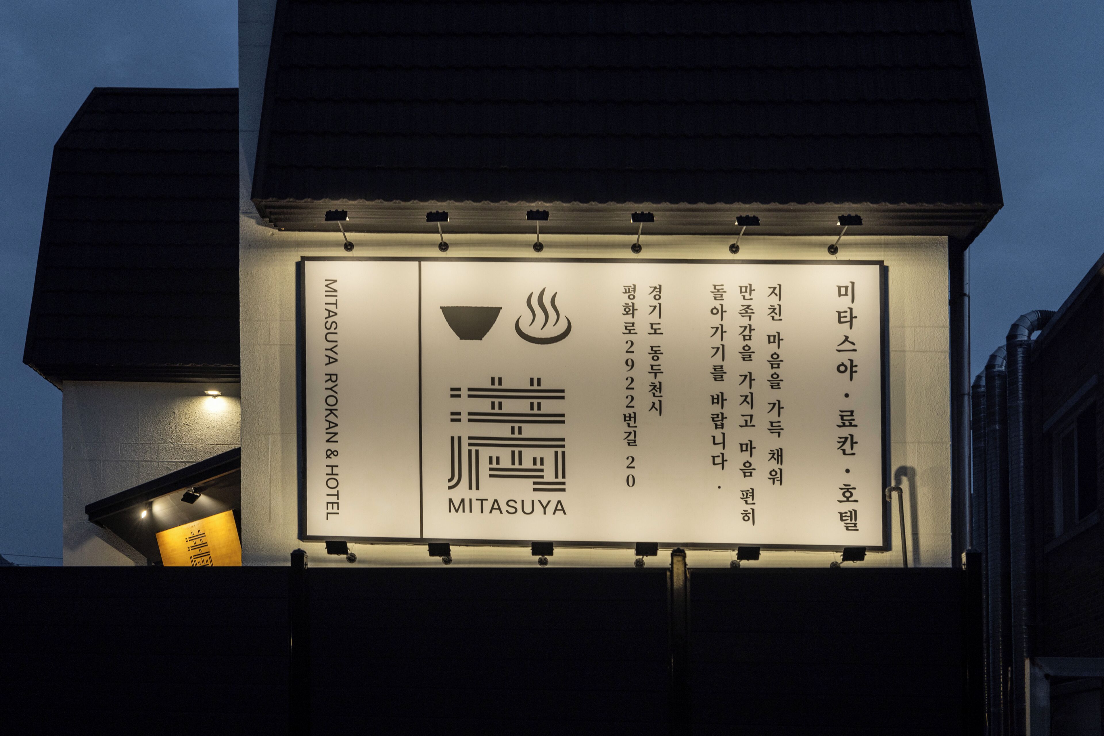 A signboard with the name 'MITASUYA' and symbols indicating amenities like a restaurant and a sauna.