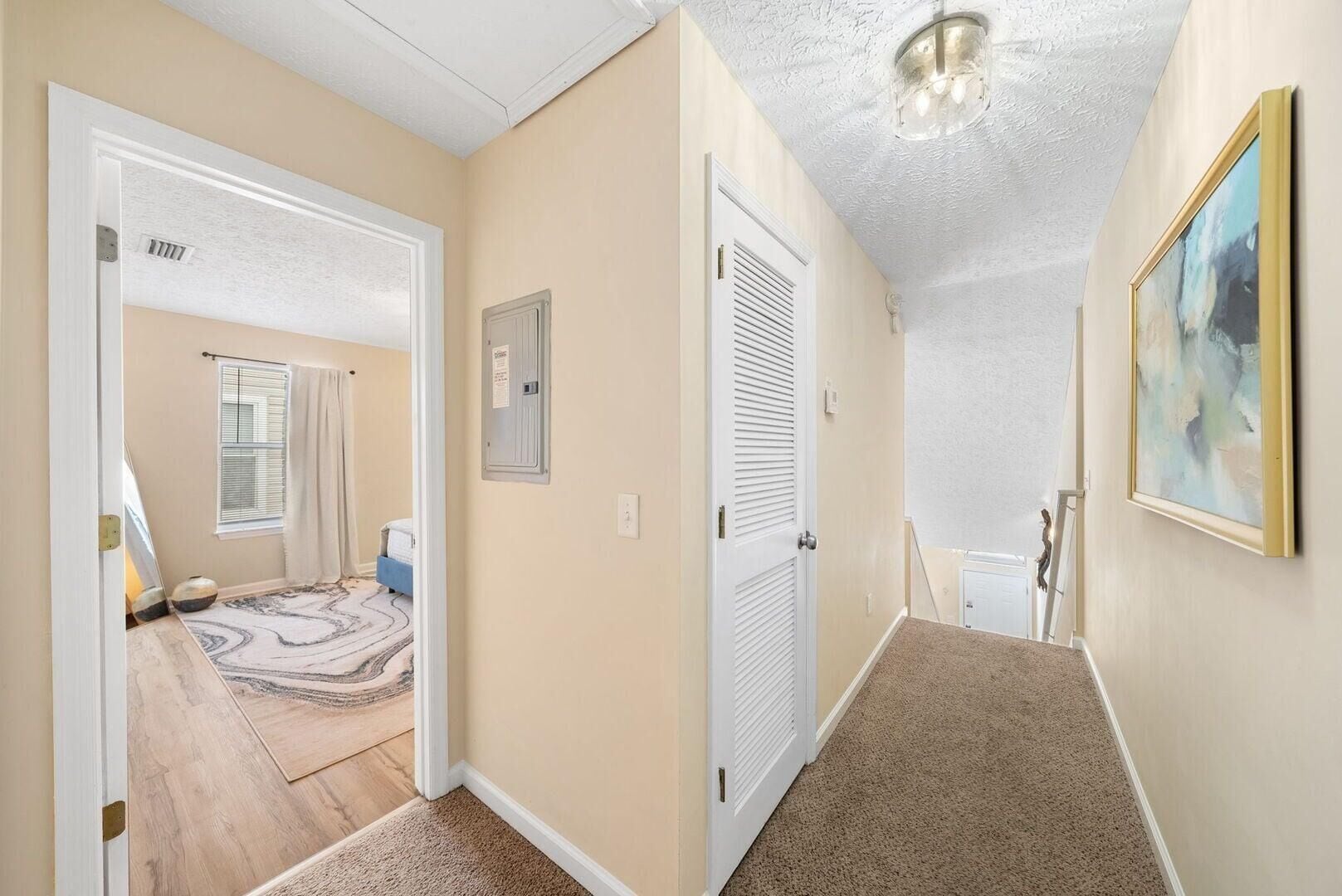 A hallway with a carpeted floor, a door with a window, and a ceiling light fixture.